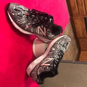 New Balance black and white stripe tennis’s shoes with orange accents.